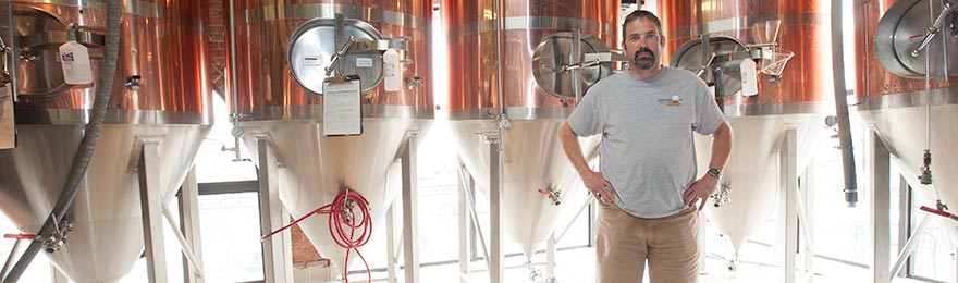 man standing in front of beer vats